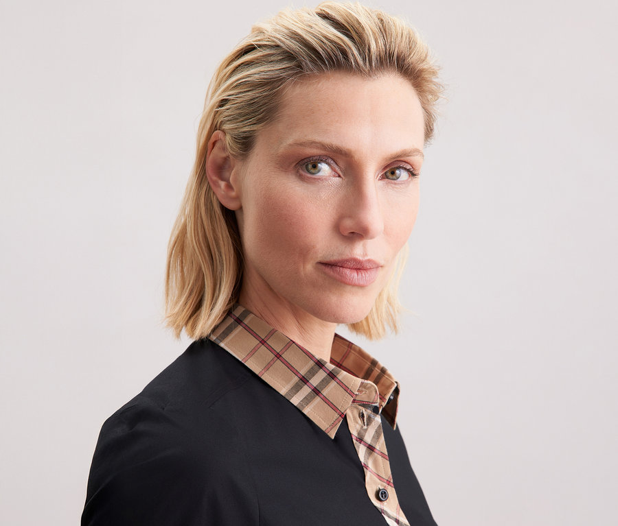 Žena má na sobě popelínovou halenku s kostkovaným detailem Seidensticker.