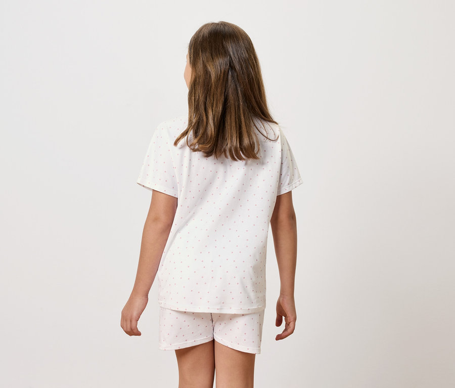 Dívka v pyžamu s krátkým rukávem a šortkami stojí zády.