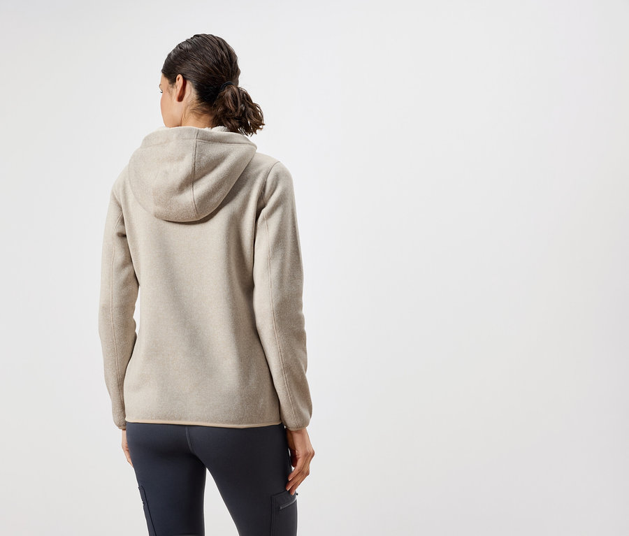 Zezadu je vidět žena v béžové mikině s kapucí a tmavě modrých kalhotách.