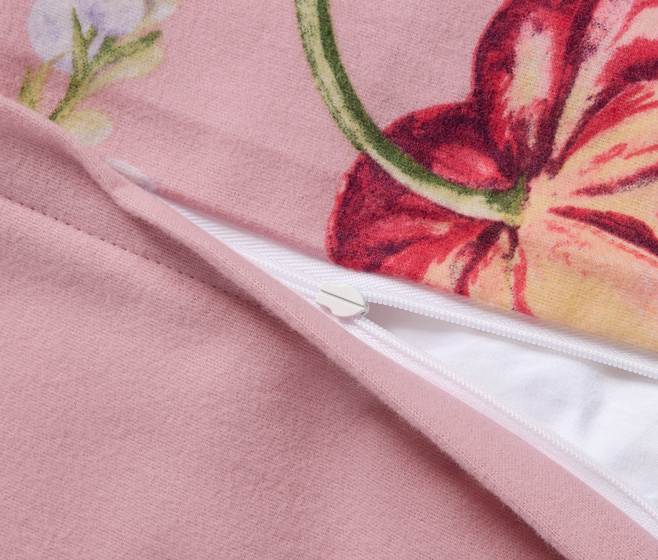 Detail růžového flanelového povlečení nadměrné velikosti s květinovým vzorem a zipem.