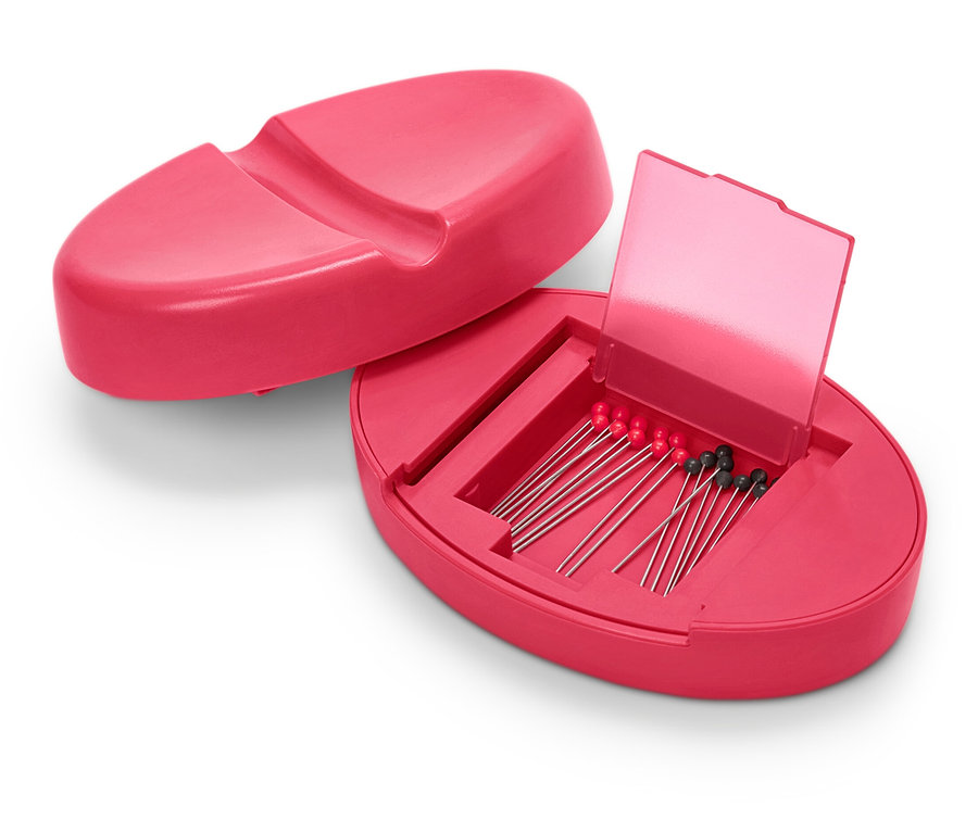 Otevřený magnetický polštářek na jehly růžové barvy s jehlami uvnitř.