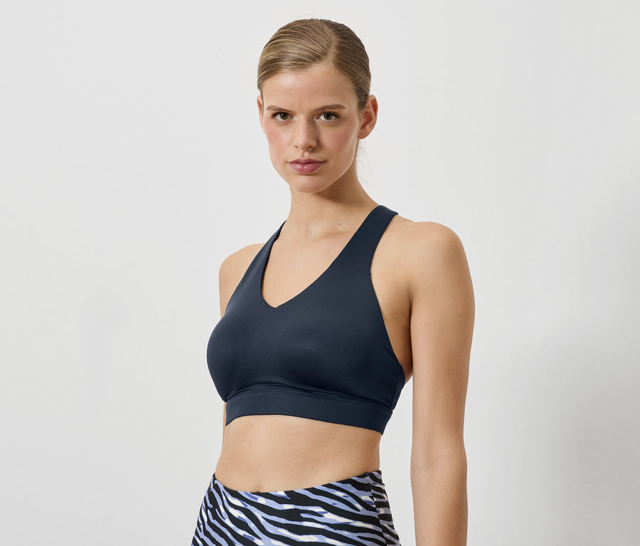 Žena má na sobě tmavě modrou sportovní podprsenku a legíny se zvířecím vzorem.