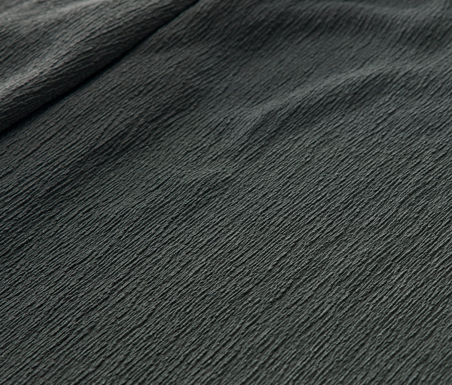 Detail zelených kalhot s nařasenou texturou.