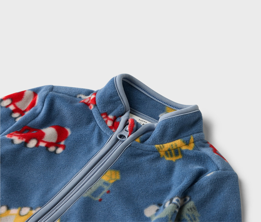Detailní záběr na modrou fleecovou bundu na zip s barevnými motivy vozidel.