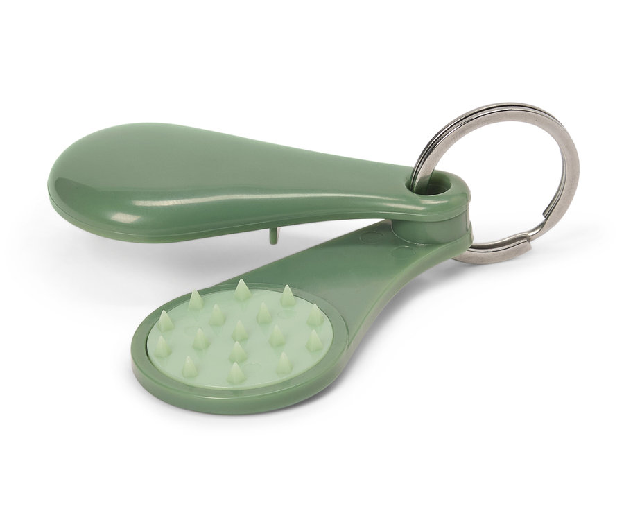 Zelený masážní přívěsek na klíče leží na bílém pozadí.