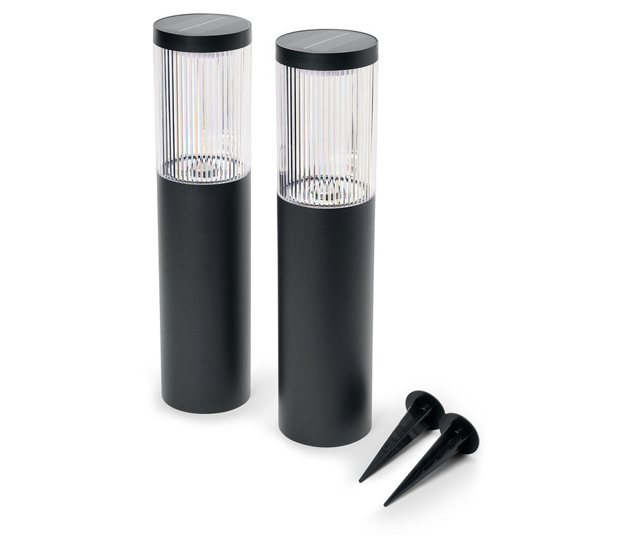 Dvě černé zahradní lampy a dva zemní hroty leží na bílém pozadí.