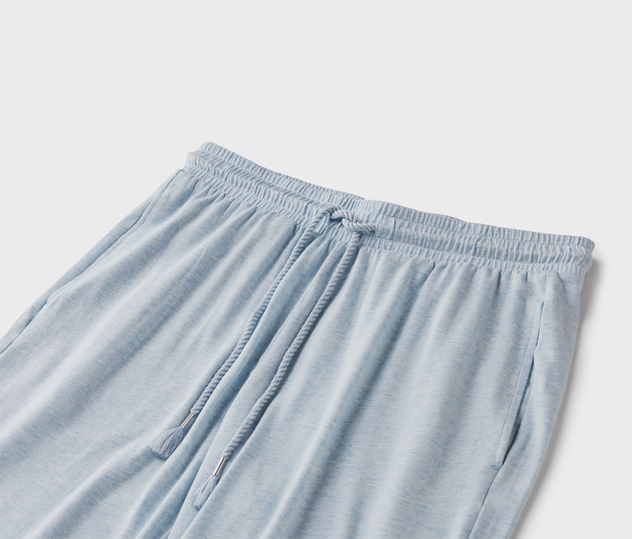 Detailní záběr světle modrých tepláků se stahovací šňůrkou.