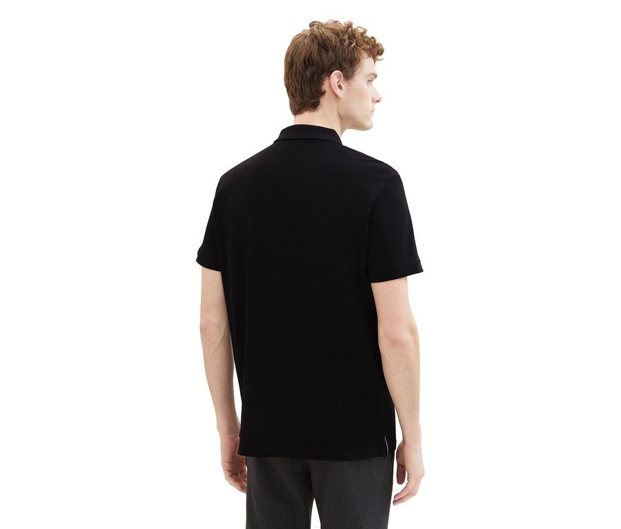 Muž zezadu v černém piké polotričku Tom Tailor.