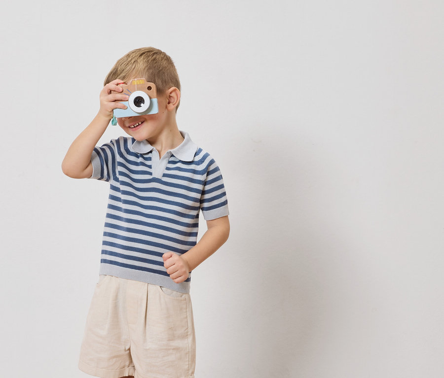 Chlapec drží hračkový fotoaparát před okem.