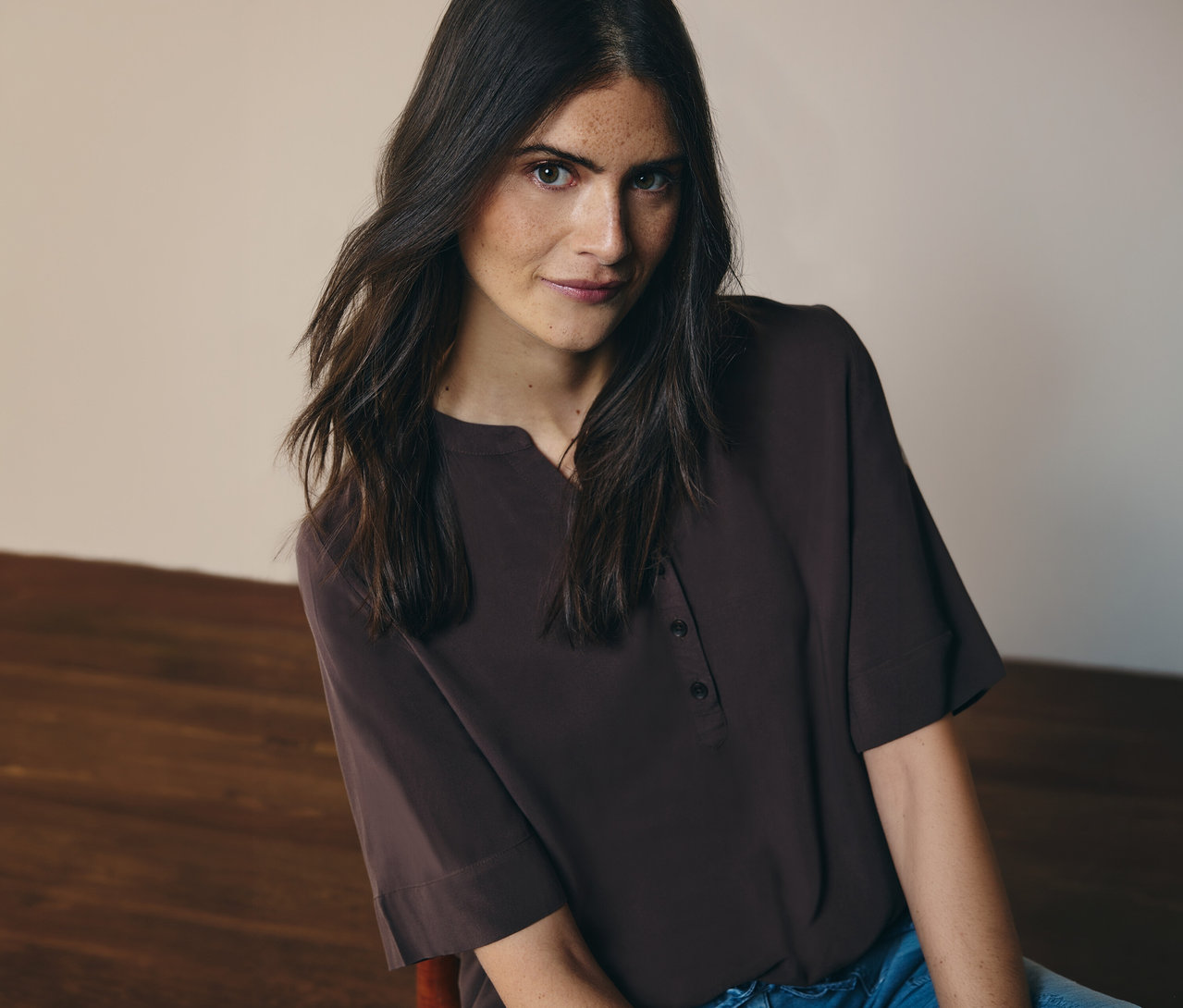 Žena má na sobě hnědou tunikovou halenku CECIL a džíny.