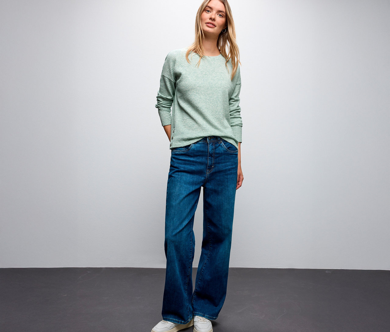 Blondýna má na sobě strukturované tričko Street One, modré džíny a bílé tenisky.