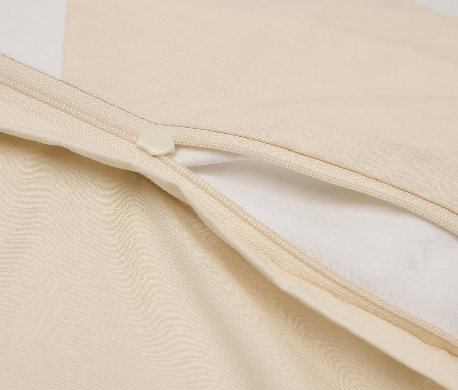 Detailní záběr částečně otevřeného krémového povlaku na peřinu se zipem.