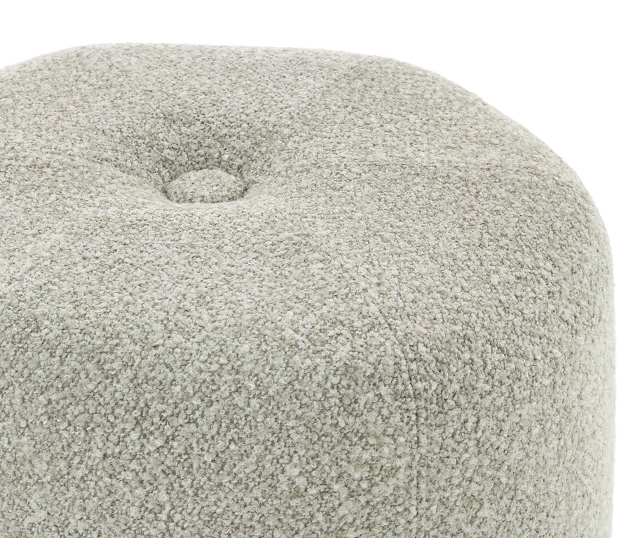 Detail světle šedé, texturované látky s jedním prošívaným knoflíkem.