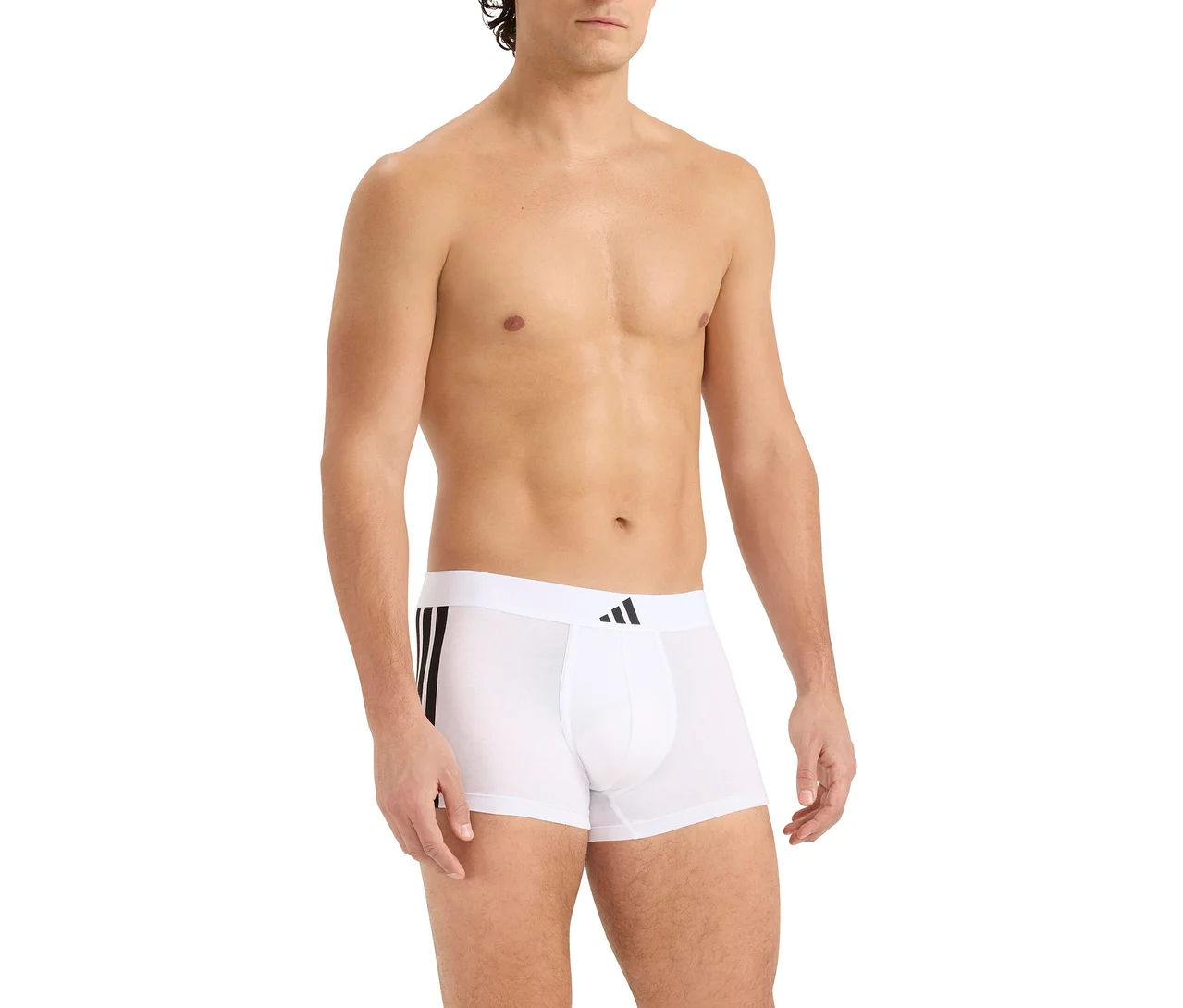 Muž bez trička v bílých boxerkách s černými pruhy na boku a černým logem Adidas na pasu.