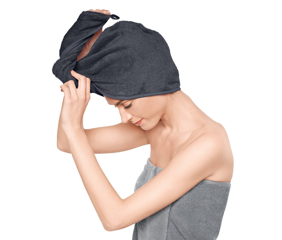 Žena si nasazuje šedý ručníkový turban.
