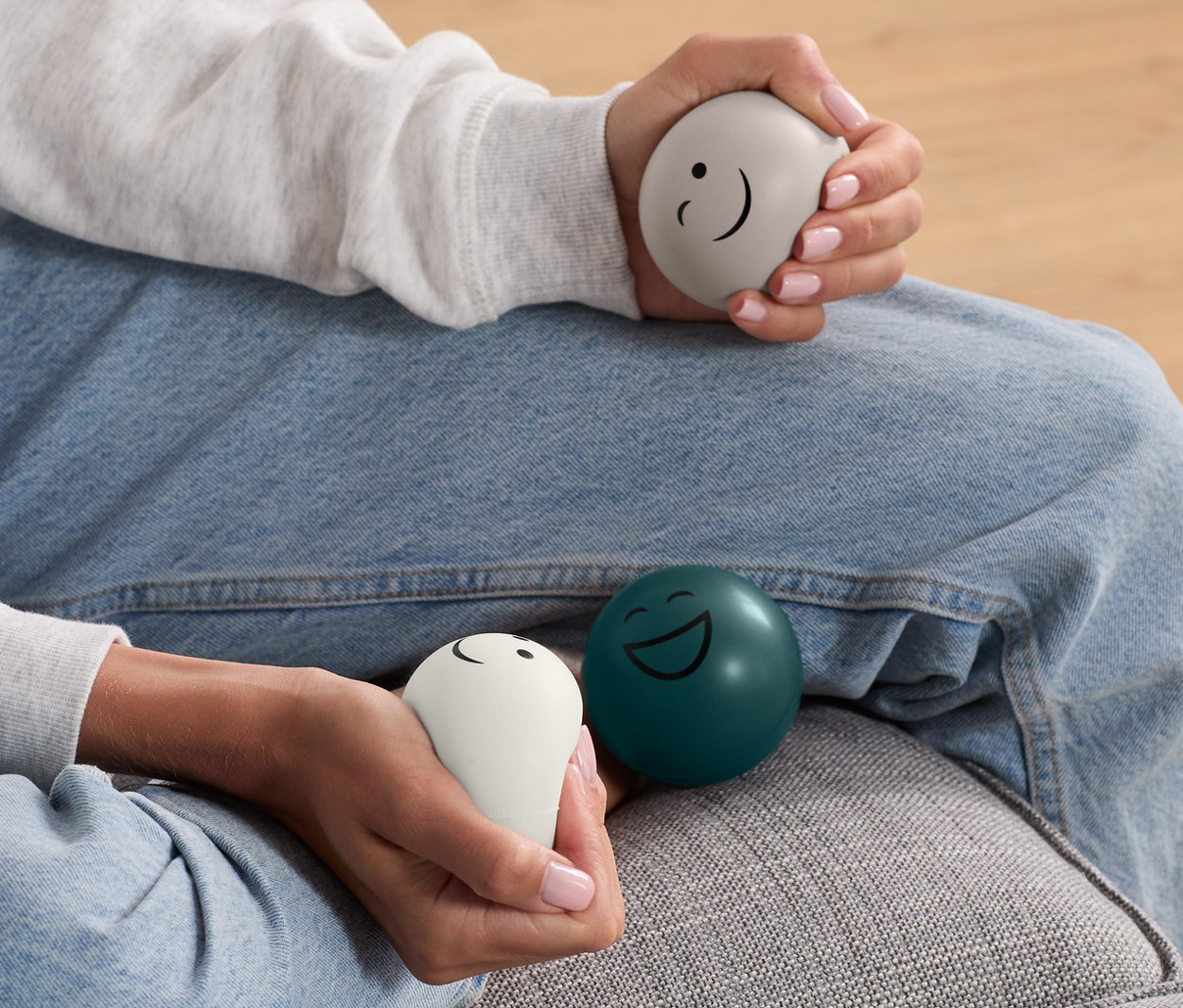 Žena sedí na gauči a v rukou drží 3 antistresové míčky.