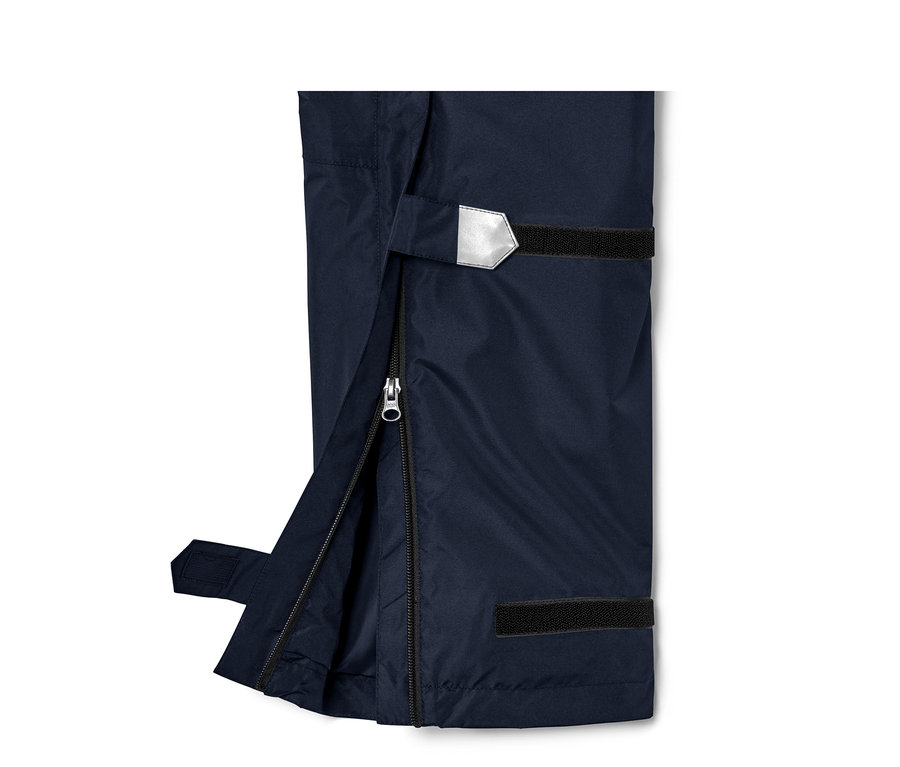 Detail high-tech kalhot do deště, unisex, s rozepnutým zipem a reflexním prvkem.