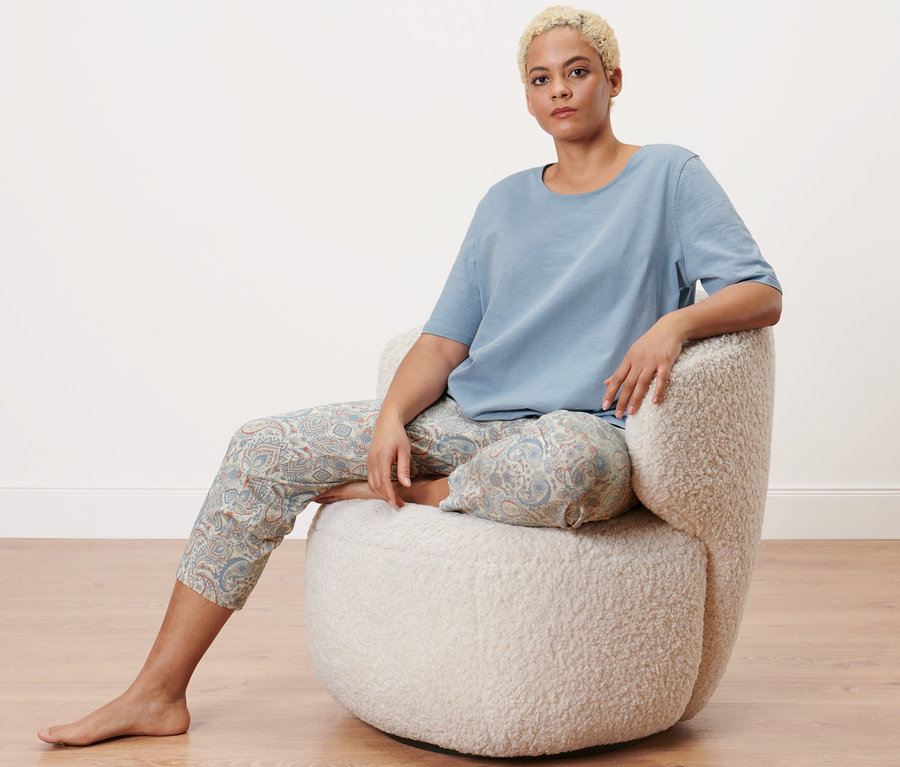 Žena sedí v křesle a má na sobě pyžamo.