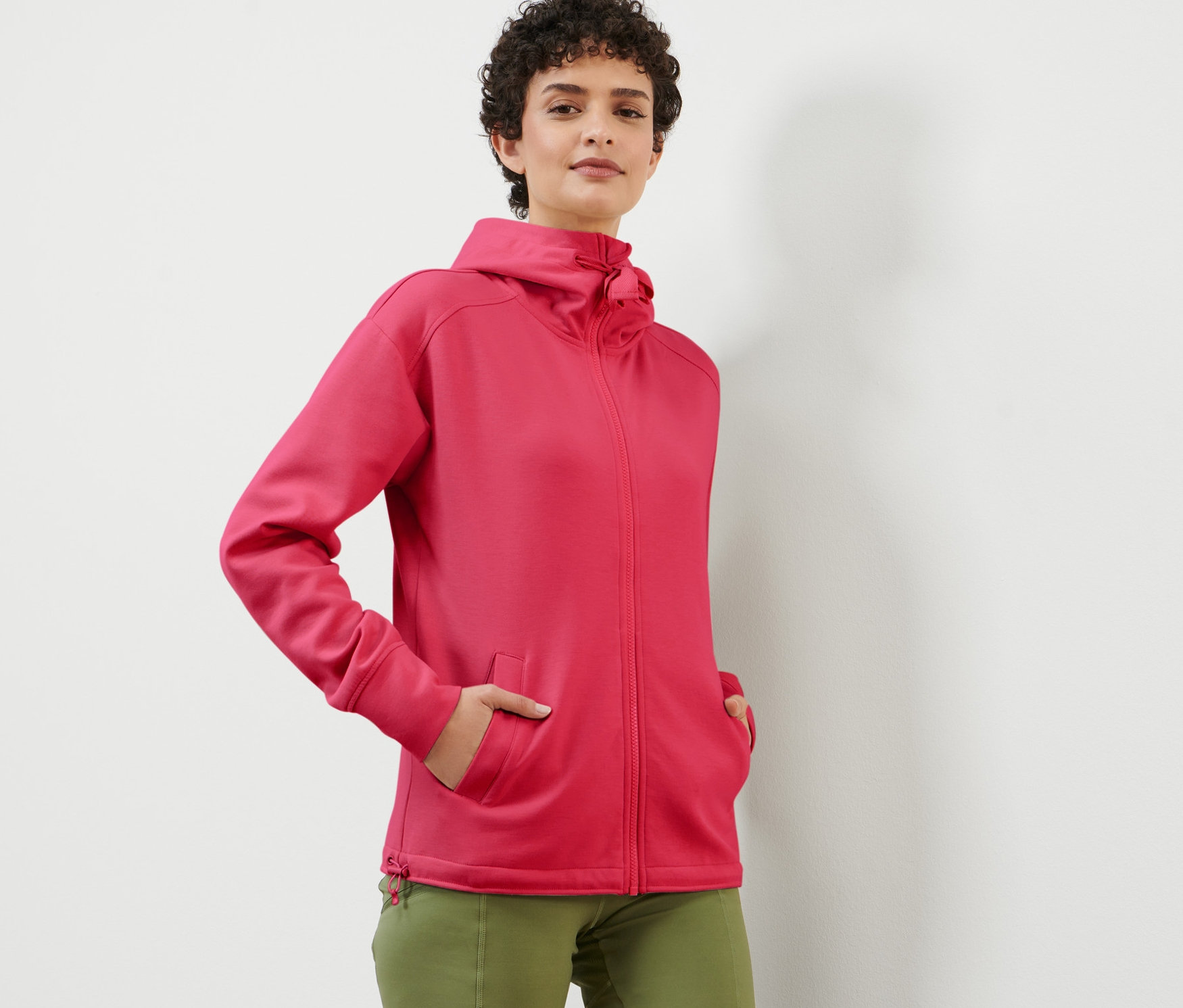 Žena pózuje v malinové mikině s kapucí.