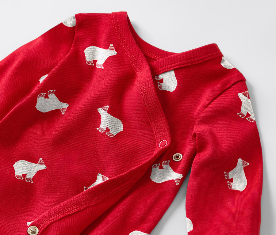 Detail červeného dětského body s dlouhým rukávem s potiskem bílých medvědů.
