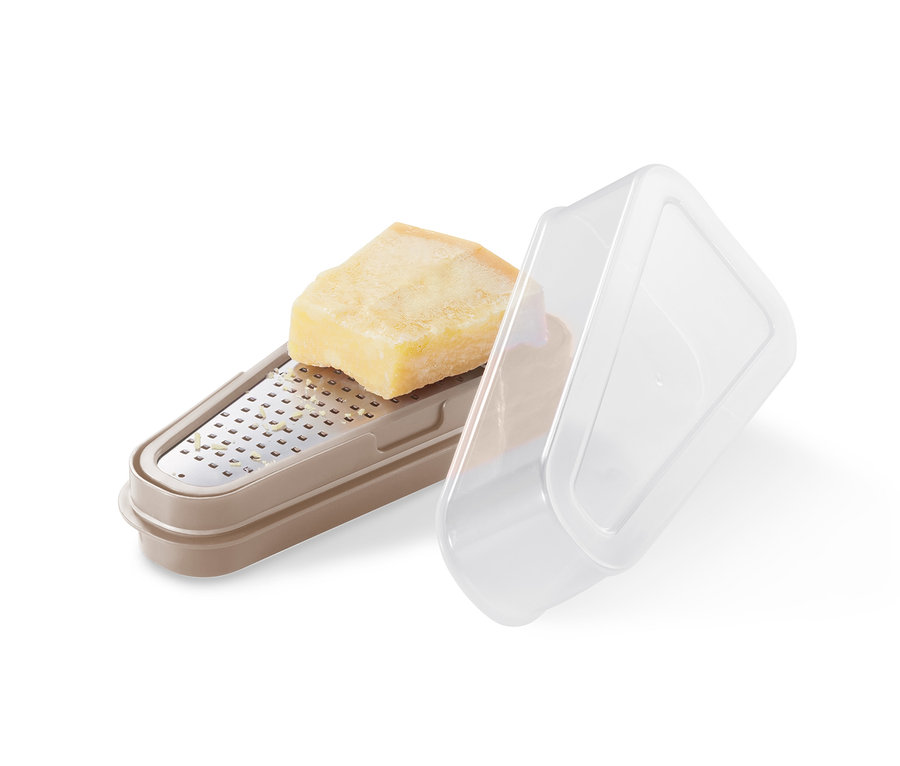 Kousek parmezánu leží na béžovém struhadle na parmezán 2 v 1 s průhledným víkem.