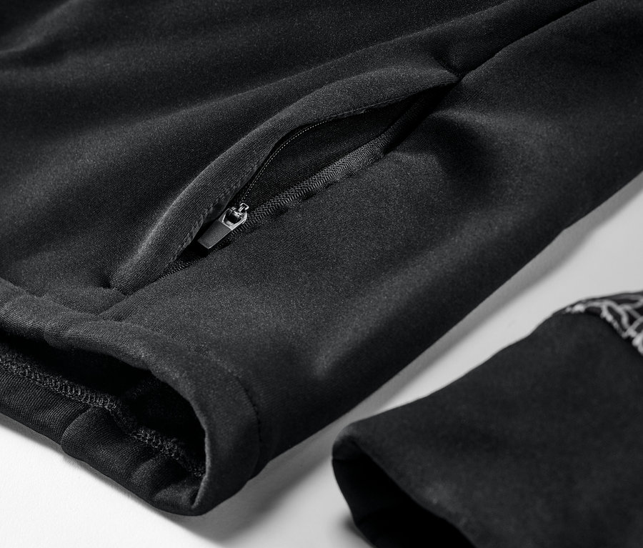 Detail černé termobundy s kapsou na zip a lemem rukávu.