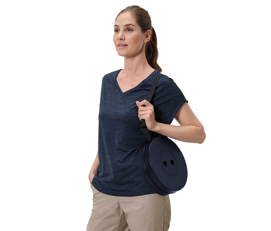 Žena nese teleskopickou kempingovou stoličku přes rameno.