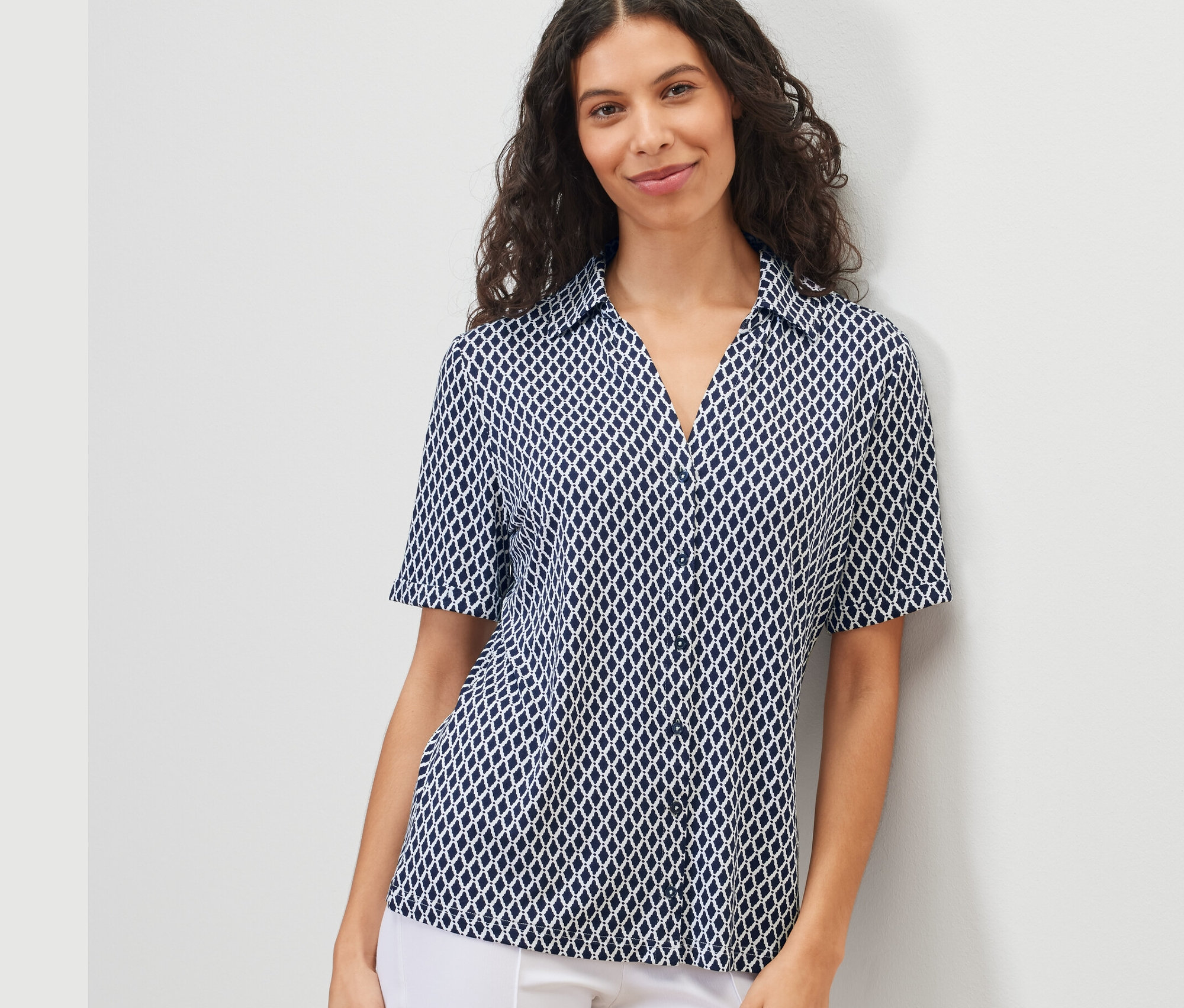 Žena má na sobě halenkové triko s knoflíkovou légou a potiskem.