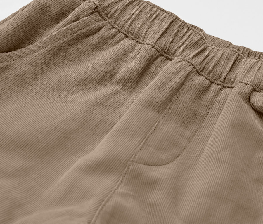 Detail dětských manšestrových outdoorových kalhot v hnědé barvě, ukazující elastický pas a kapsu.