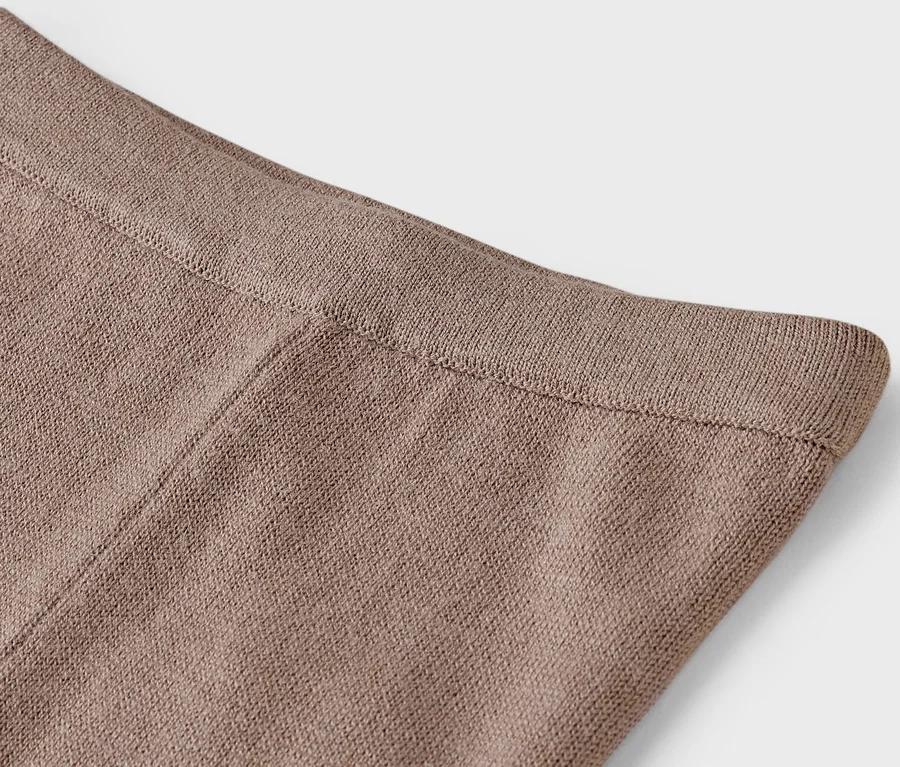 Detailní záběr na horní část hnědých pletených kalhot.