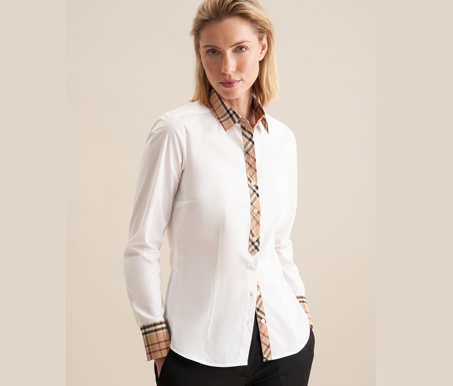 Žena má na sobě bílou popelínovou halenku Seidensticker s kostkovanými detaily.