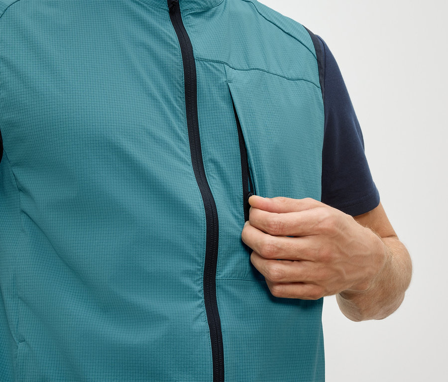 Muž otevírá kapsu na zip petrolky vesty.