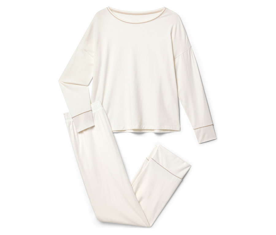 Krémové pyžamo s dlouhým rukávem a kalhotami leží na bílém pozadí.