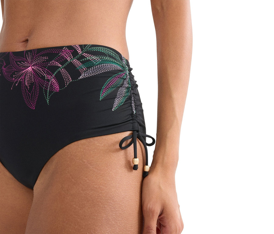 Detailní záběr ženy v černých bikinových kalhotkách s květinovovým vzorem.