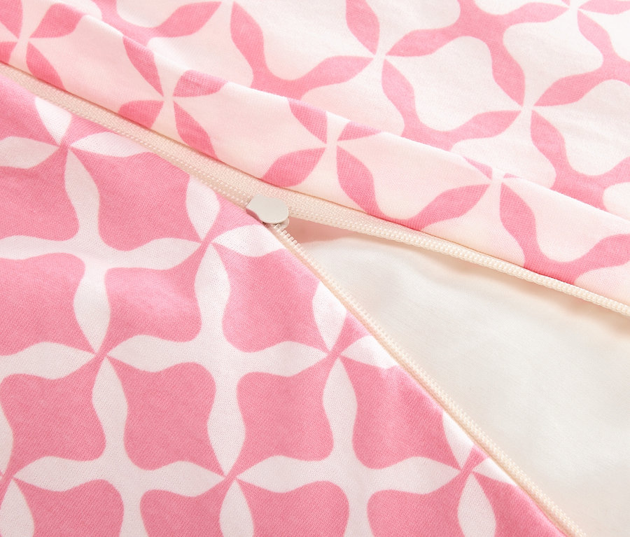 Detailní záběr na částečně otevřený zip na růžovo-bílé vzorované látce.