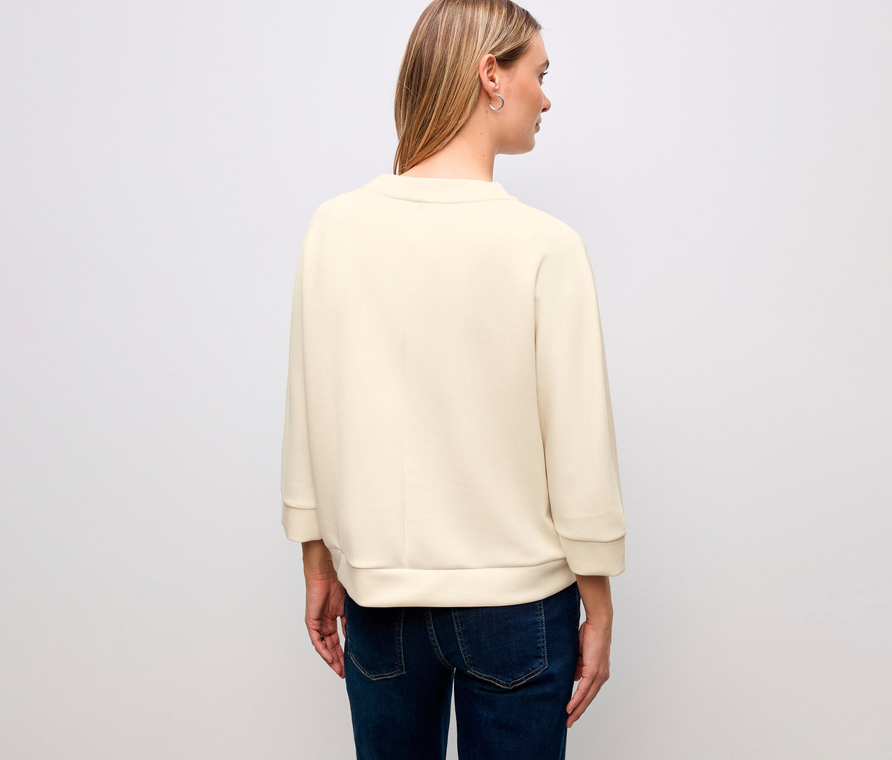 Pohled zezadu na ženu s blond vlasy v tričku ze směsi modalu Street One a džínách.