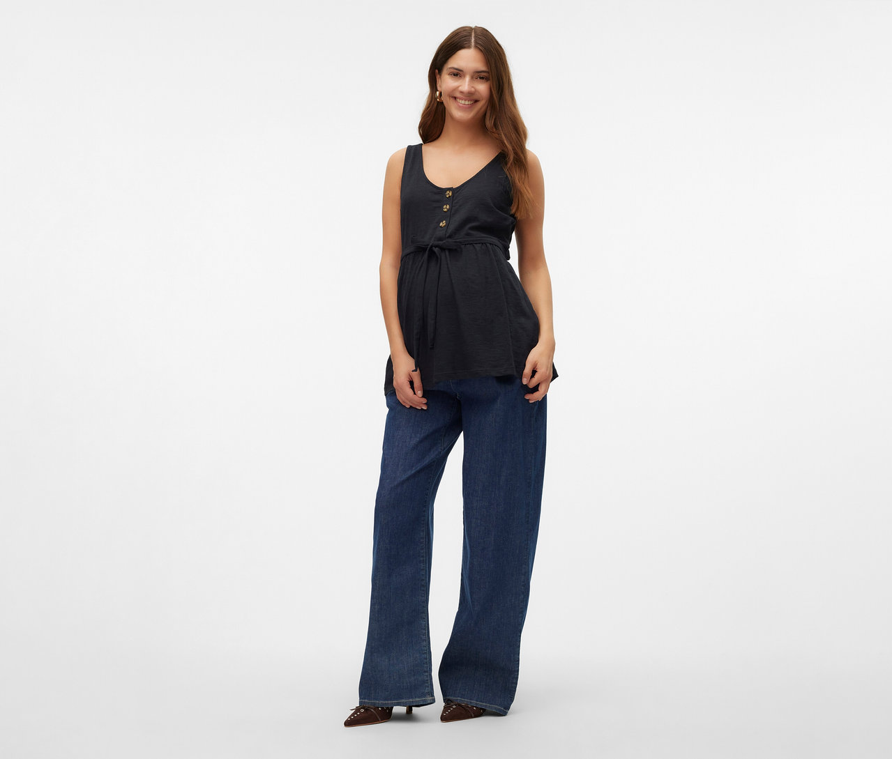 Žena má na sobě top na kojení MAMALICIOUS »MLEVI LIA«, džíny a boty.