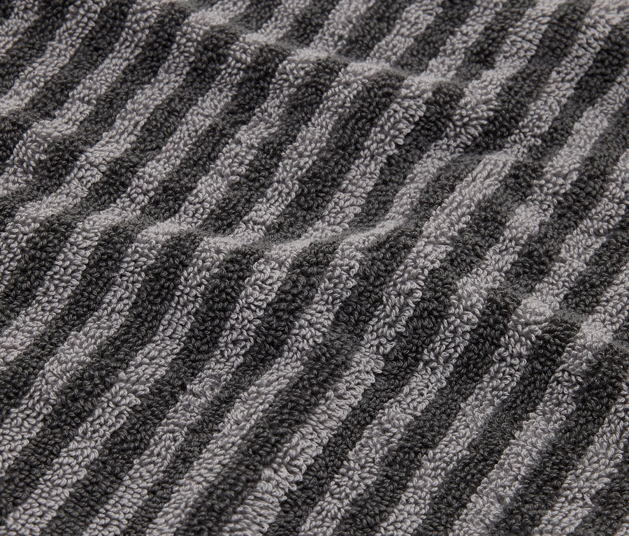 Detailní záběr na pruhovaný ručník v odstínech šedé a černé.