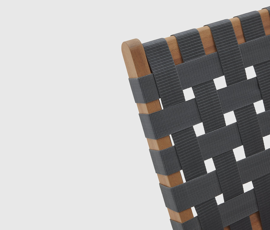 Detailní pohled na židli s dřevěným rámem a tkaným, šedým sedákem.