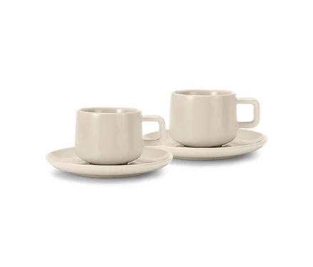 Dva béžové šálky na espresso s podšálky, stojící vedle sebe.