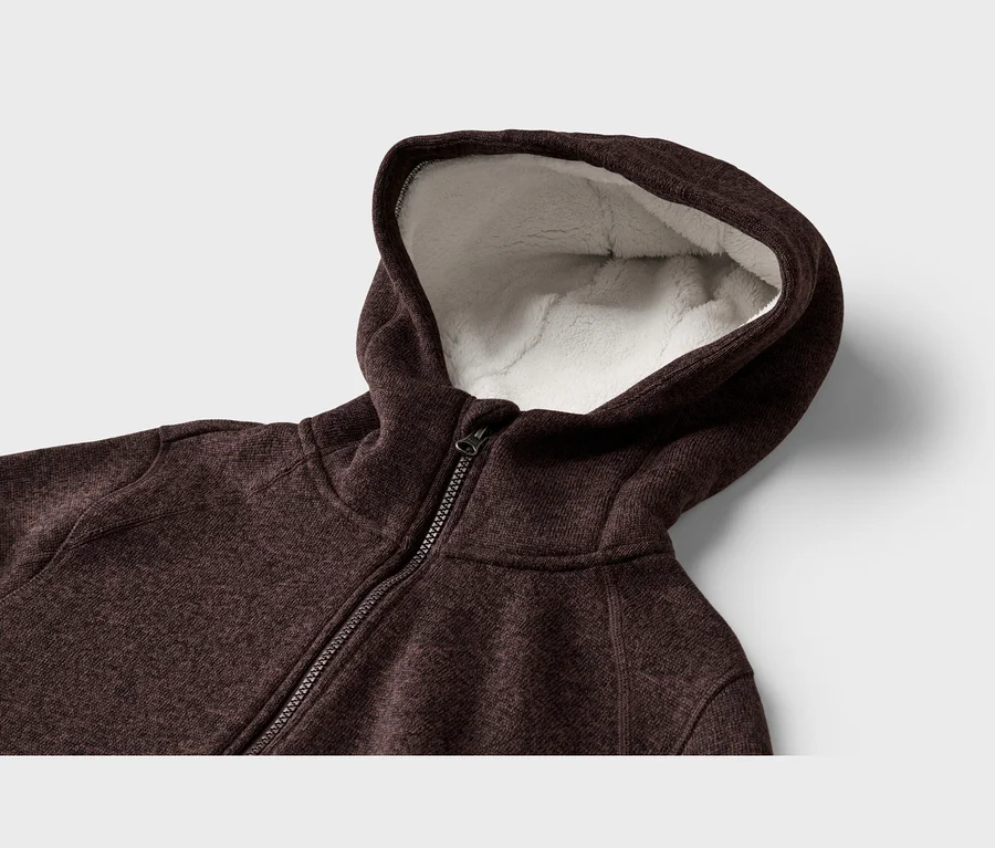 Detail tmavě hnědé melírované mikiny s kapucí na zip, s nadýchanou bílou sherpa podšívkou v kapuci.