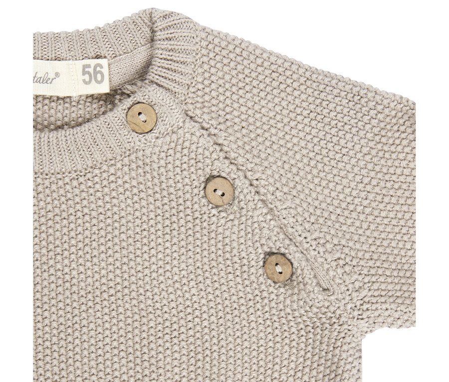 Detail béžového pleteného svetru se třemi kulatými dřevěnými knoflíky na rameni a štítkem s velikostí 56.