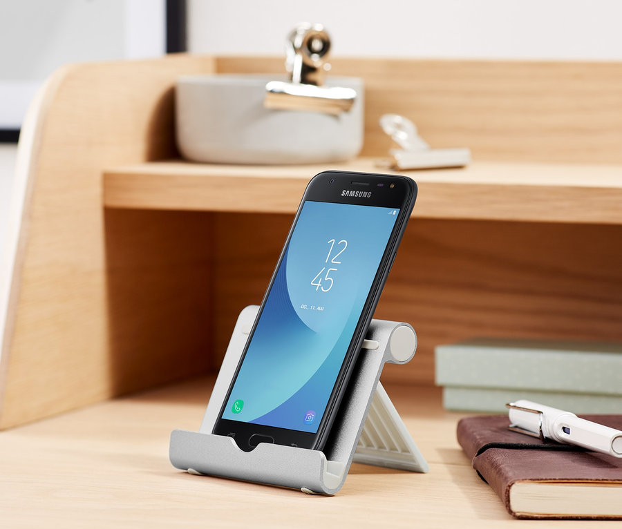 Černý smartphone je umístěn ve stojánku na smartphone a tablet na stole.