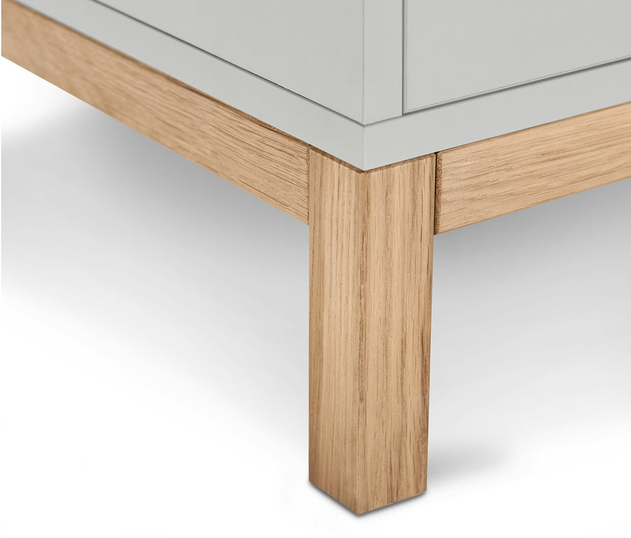 Detail spodní části světle šedé koupelnové skříňky pod umyvadlo Eklund se dvěma zásuvkami a světlými dřevěnými nohami.