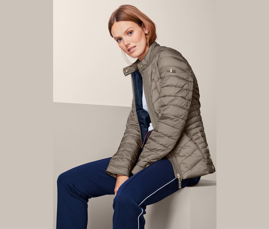 Žena sedí a má na sobě prošívanou bundu.