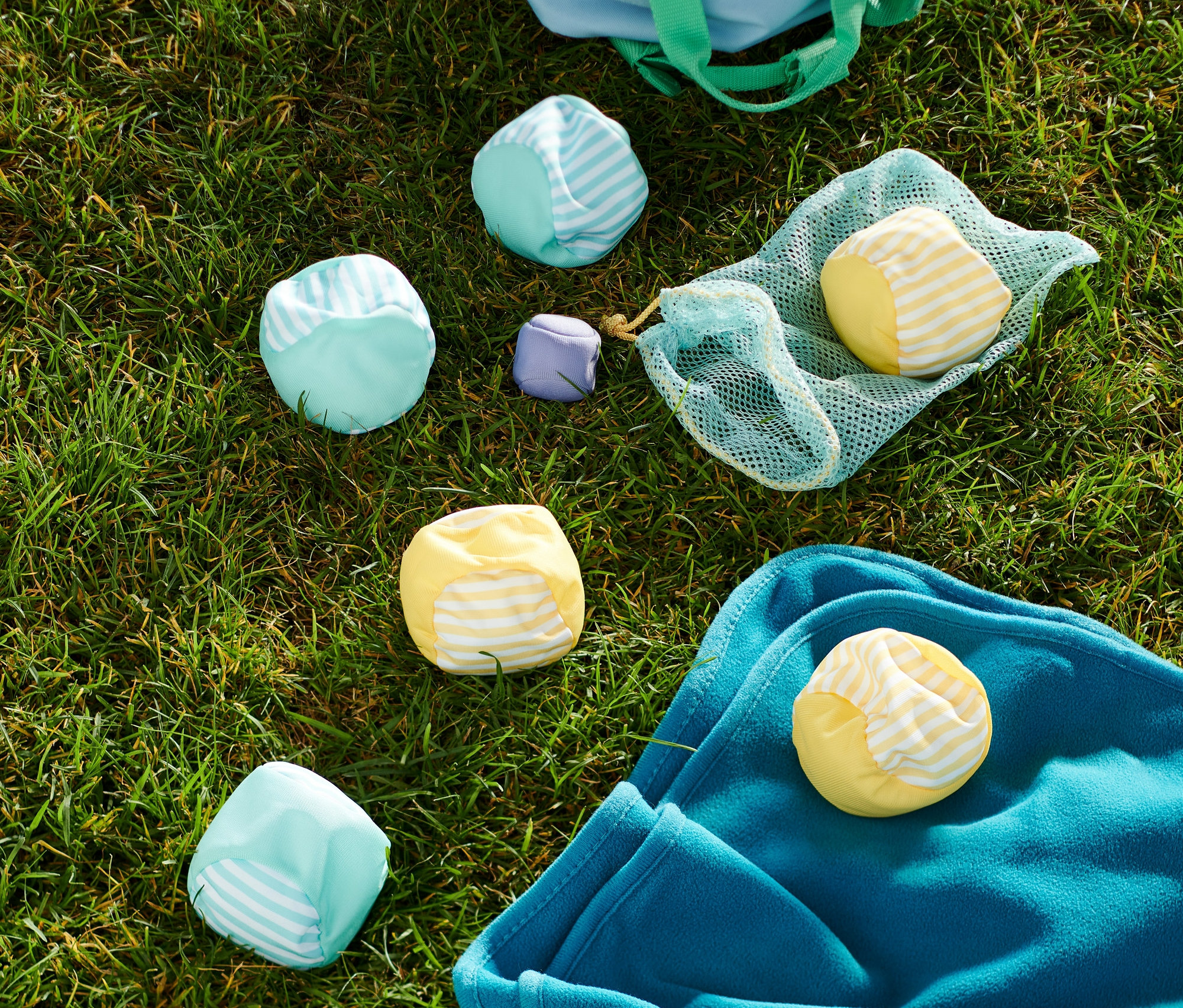 Na trávě leží hra Soft boccia, modrá taška a modrá deka.