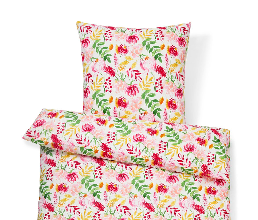 Bílé povlečení s květinovým vzorem: polštář, přikrývka a malý polštářek.