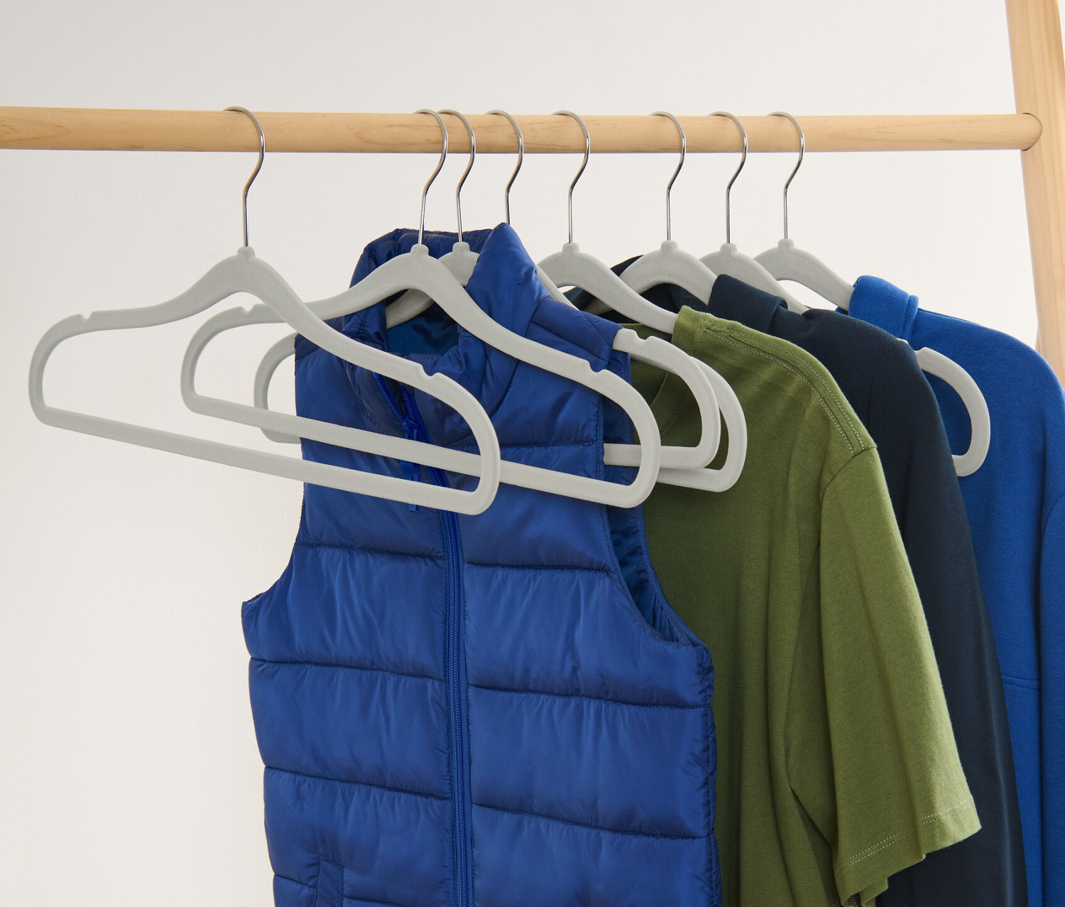 Modrá vesta a barevné oblečení visí na osmi extra úzkých ramínkách na šaty.