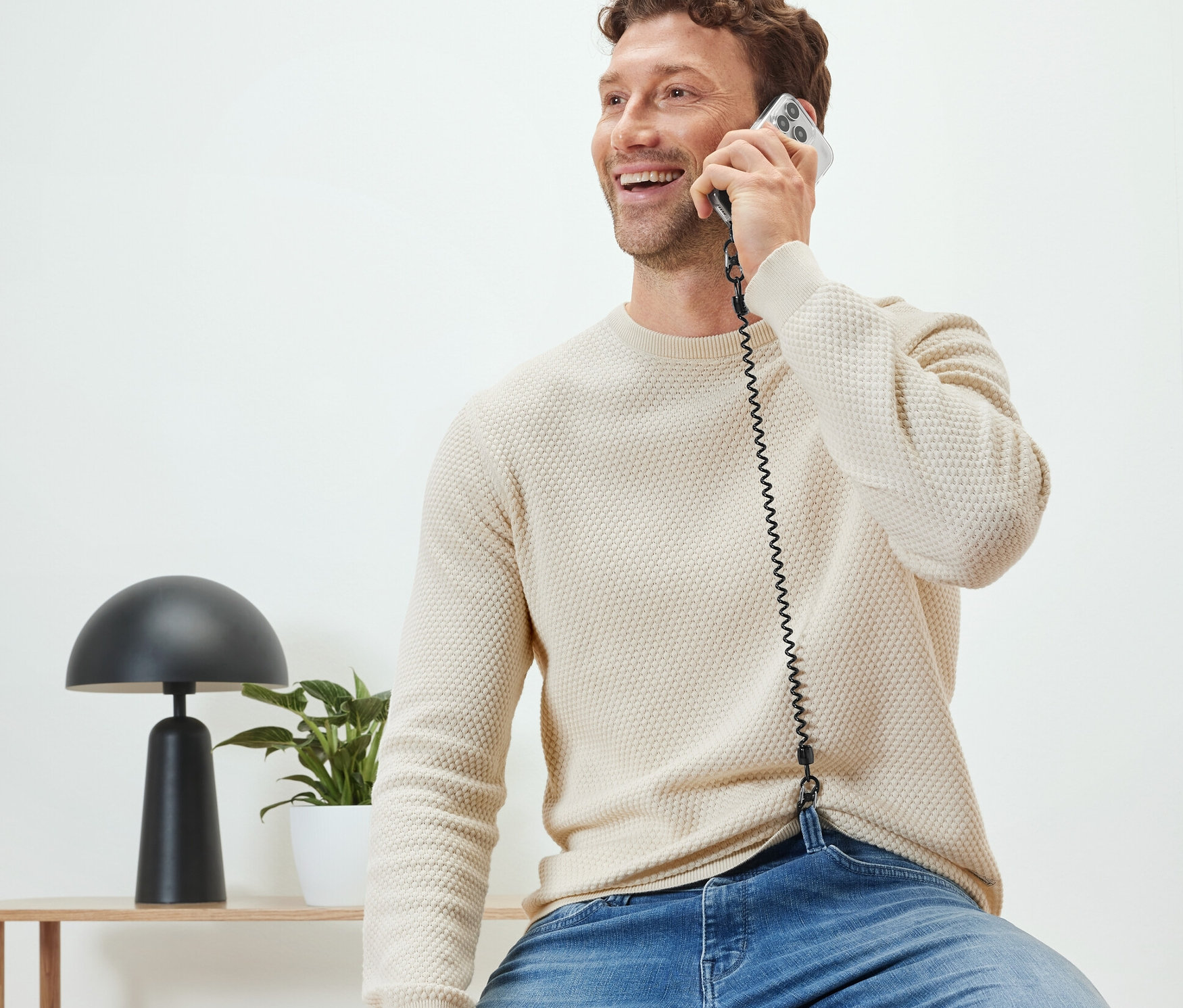 Muž sedí a telefonuje s bezpečnostním řetízkem na mobil.