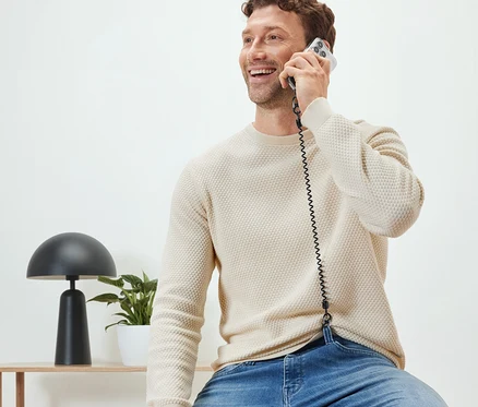 Muž sedí a telefonuje s bezpečnostním řetízkem na mobil.